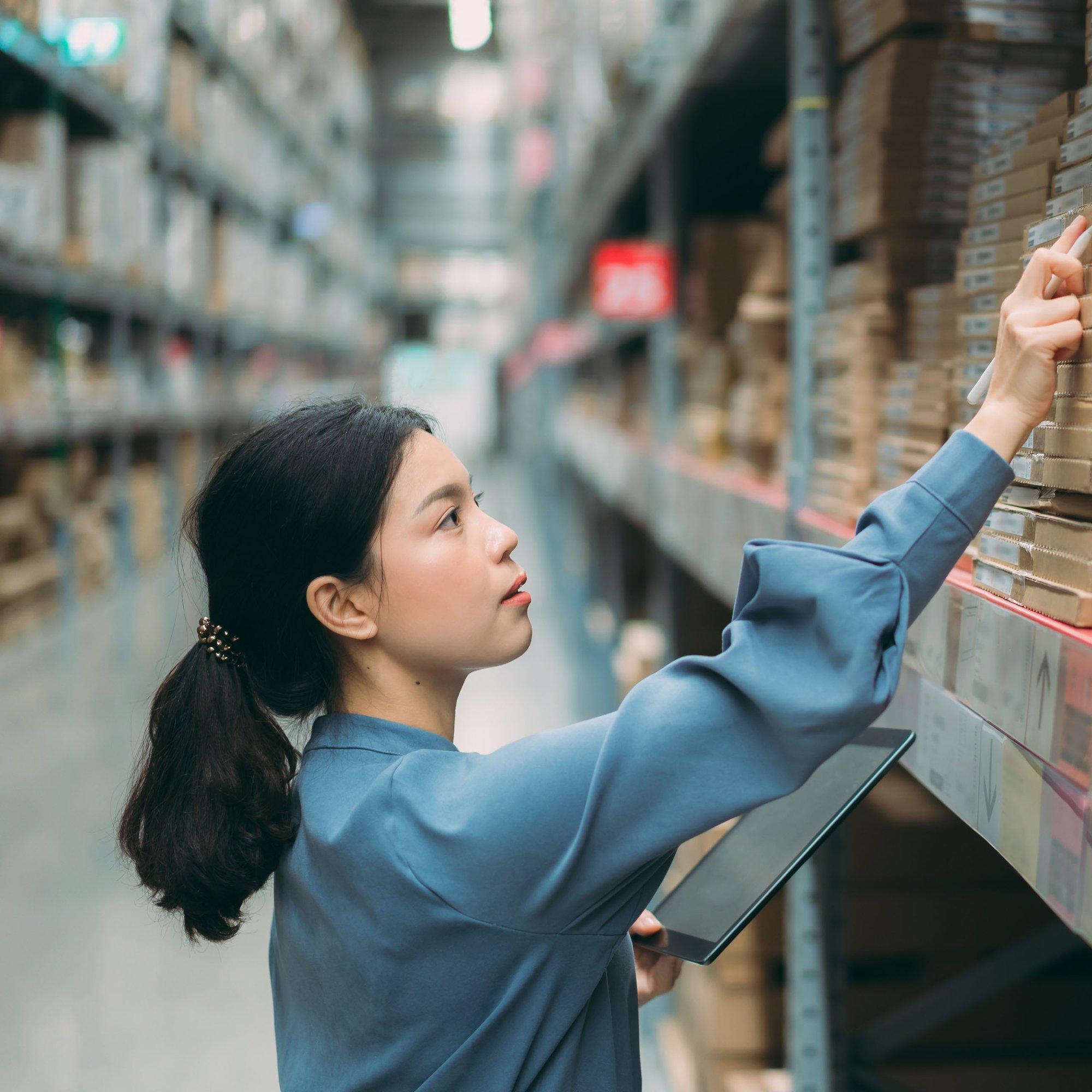 Female procurement employee reviewing warehouse inventory for gaps and potential supplier billing errors.