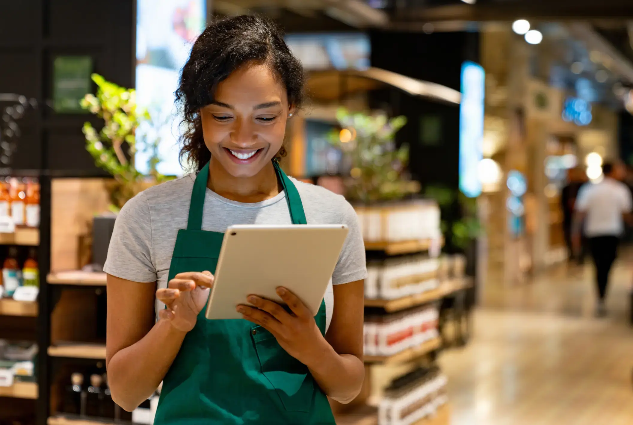 Happy African American retail clerk working at the supermarket using a digital tablet.
